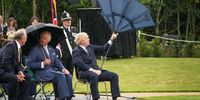 STAFFORD, ENGLAND - JULY 28: Prince Charles, Prince of Wales looks on as (C) British Prime Minister, Boris Johnson (R) opens his umbrella at The National Memorial Arboretum on July 28, 2021 in Stafford, England. The Police Memorial, designed by Walter Jack, commemorates the courage and sacrifice of members of the UK Police service who have dedicated their lives to protecting the public. The memorial is set on grounds landscaped by Charlotte Rathbone within the National Memorial Arboretum and stands along with 350 memorials for the armed forces, civilian organisations and voluntary bodies who have played their part serving the country. (Photo by Christopher Furlong - WPA Pool/Getty Images)