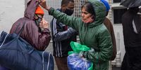 Volunteer Pat Pillay gives a homeless man an orange beanie to wear and covers his head for him.  (Photo: Ashraf Hendricks)