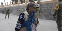 A woman covers her mouth as she walks near soldiers cleaning a street from the ash of Popocatepetl volcano, in the Santiago Xalitzintla community, municipality of San Nicolas de los Ranchos, Puebla, Mexico 23 May 2023. Some 60 soldiers in different brigades worked to remove a dense layer of volcanic ash that Popocatepetl dropped in recent days on the streets of the community, the closest to the active colossus, just 12 kilometers away.  EPA-EFE/Hilda Rios