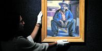 A gallery assistant poses with Gerard Sekoto’s Portrait of a Man in London on <br>10 September 2018. (Photo: Barbara Lindop)<br>Photo: Neil Hall/EPA-EFE