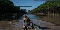 ZHUOZHOU, CHINA - AUGUST 05: A man pulls a bag  full of goods salvaged from a building as he wades through receding floodwaters on August 5, 2023 in Zhuozhou, Hebei Province south of Beijing, China. The extreme rainfall from Typhoon Doksuri was the heaviest to hit Beijing in 140 years, inundating the capital and triggering flash floods and landslides. In nearby Hebei province, where some areas were flooded with water diverted from Beijing, officials said floodwaters could take a month to recede.  More than 100,000 people were evacuated from the hard-hit city of Zhuozhou, where rescuers used rafts to reach people trapped in villages cut off by deep water. (Photo by Kevin Frayer/Getty Images)