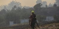 A firefighter in Walmer Estate, Cape Town on 19 April 2021. Behind him is a small settlement where a community has erected several shacks. Some of the structures were razed in the blaze. (Photo: Leila Dougan)