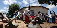 Poet and traditional healer, Sisonke Papu, dances around the stool sculptures shortly after their arrival, during a ceremony to welcome and bless them before they are taken into the homestead's kraal. Photo by Malibongwe Tyilo
