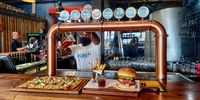 Barman Vusi Ngena pulls a Robsons West Coast ale to go with this burger and pizza. (Photo: Wanda Hennig)<br>
