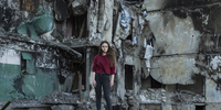 "Katya Baranivska, Borodyanka". Katya Baranivska (22) standing in front of the building where her family’s apartment used to be, before it was destroyed by Russian bombing. Borodyanka, Ukraine. The Russian invasion of Ukraine has become a particularly brutal affair because of the heavy civilian losses and the destruction of civilian infrastructure. Since Russia launched its full-scale invasion more than 100,000 buildings have been destroyed and civilian casualties are impossible to calculate. The indiscriminate bombing of apartment blocks and residential neighbourhoods all over the country, as well as railway stations, public transport hubs, and shopping malls, have shown the unprecedented brutality of the Russian Army. Tragically, as the war continues, people living in Ukraine are getting used to it. While they continue to fight, many are trying to return to their routines, with the war becoming a haunting background to their daily lives. And, as some territories return to Ukrainian control, they reveal the atrocities and destroyed homes left behind. © Sasha Maslov, Ukraine, Shortlist, Professional competition, Portraiture, Sony World Photography Awards 2023