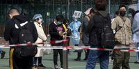 A health worker wearing personal protective equipment (PPE) holds a sign marking the end of the line as residents queue at a Covid-19 testing facility in Hong Kong, China, on Tuesday, Feb. 15, 2022. Hong Kongs leader said the city had no plans for a citywide lockdown to help bring cases back to zero, even as she acknowledged that a growing omicron outbreak has exceeded its capacity to respond.