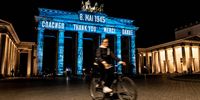 A cyclist passes by the Brandenburg Gate illuminated with the word ‘Thank You’ in various languages to mark the 75th anniversary of the end of World War Two in Berlin.  (Photo: EPA-EFE / Filip Singer)
