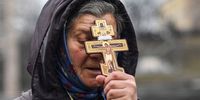 A religious woman holds a cross as she prays on Independence square in Kyiv in the morning of February 24, 2022.<br>Air raid sirens rang out in downtown Kyiv today as cities across Ukraine were hit with what Ukrainian officials said were Russian missile strikes and artillery. - Russian President announced a military operation in Ukraine on February 24, 2022, with explosions heard soon after across the country and its foreign minister warning a "full-scale invasion" was underway. (Photo by Daniel LEAL / AFP)