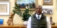 Professor Ntobeko Ntusi in front of a painting depicting student protests, inside his office at Groote Schuur Hospital – the same office once occupied by his mentor, the late Professor Bongani Mayosi. (Photo: Biénne Huisman / Spotlight)