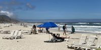 Beachgoers at Camps Bay beach watching the sea. Image_ Siyabonga Goni