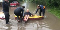 An elderly Stanford resident is helped to safety from his flooded home. (Photo: Rodney Ackermann)