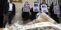 epa09300437 Members of RSF, Reporters Sans Frontieres (Reporters Without Borders) hold pages of Hong Kong-based Apple Daily newspaper in front of a mock coffin and funeral bouquet of flowers during a protest against the closure of the newspaper, outside the Chinese Embassy in Paris, France, 25 June 2021. The last edition of the paper rolled off the presses on 23 June, three days earlier than expected, after taking into consideration the safety of its staff and manpower. The newspaper shut down after Hong KongÕs national security police arrested five directors at the newspaper on suspicion of conspiracy to collude with foreign forces under the China-imposed legislation.  EPA-EFE/IAN LANGSDON