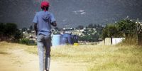 A youth walks past empty drums put down by residents of Koppermyn section in Maja village during the Covid-19 lockdown. A truck delivers water once a week to parts of the village which are not connected to the water supply. The water is rationed.(Photo: Lucas Ledwaba / Mukurukuru Media)