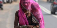 An Indian woman carrying her child walks covered with a scarf to protect themselves from excessive heat in Ahmedabad, Gujarat state, western India, 15 June 2025.  EPA-EFE/RAJAT GUPTA