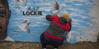 An Eldorado Park resident writes a message on the mural. (Photo: Shiraaz Mohamed)