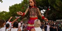 ATHENS, GREECE - SEPTEMBER 02: Little Amal, a giant puppet depicting a young refugee girl, and Athenians perform 'Ariadne's Thread' from Ancient Greek mythology while walking in the city on September 2, 2021 in Athens, Greece. Little Amal is a 3.5 metre puppet walking 8,000 kilometres across Europe to highlight the plight of child refugees. There are some 26 million refugees worldwide, more than half of them are children. (Photo by Milos Bicanski/Getty Images)