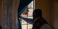Maboyisi Maneli shows how he has taped paper to his cracked windows to keep the cold out at his unit at the city-owned Annie Burger Old Age Home. (Photo: Julia Evans)