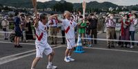KAMINOYAMA, JAPAN - JUNE 06: Torch bearers laugh as they pose for photographs as they exchange the flame during the Olympic torch relay on June 6, 2021 in Kaminoyama, Japan. As the Olympic torch relay makes its way around Japan, much of the original route has been altered or cancelled completely as prefectural authorities act to avoid large gatherings while the country endures a fourth wave of coronavirus. (Photo by Carl Court/Getty Images)