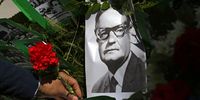 A man leaves a flower next to a picture of Allende. (Photo: EPA / Elvis Gonzalez)