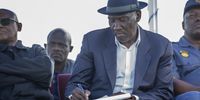 Police Minister Bheki Cele takes notes during a community meeting in at a sports field in Hermanus, 24 July 2018. Cele met with community leaders after violent service delivery and housing protests rocked the small town over the past few weeks. 60 people have been arrested and a firearm has gone missing which Cele demanded back during the mass meeting. Photo: Leila Dougan