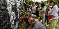 epa10016538 People put candles and flags at a mural dedicated to Roman Ratushny on a wall in Kyiv (Kiev), Ukraine, 16 June 2022. Ratushny, a prominent Ukrainian political activist and serviceman, was killed in combat action in the Kharkiv region on 09 June. On 24 February Russian troops had invaded Ukraine causing fighting and destruction and a humanitarian crisis in the country.  EPA-EFE/OLEG PETRASYUK