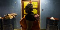 A woman walks past old oil drums that have been placed on each floor of the seven-storey building to dispose of rubbish. (Photo: Shiraaz Mohamed)