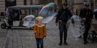 epa09905495 Children play with giant soap bubbles, in the city of Leopolis, Ukraine, 23 April 2022. Russian troops entered Ukraine on 24 February resulting in fighting and destruction in the country and triggering a series of severe economic sanctions on Russia by Western countries.  EPA-EFE/MIGUEL GUTIERREZ