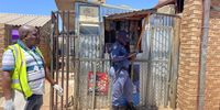 A SAPS officer and member of a health inspector team stand outside a shop in Naledi, Soweto where a banned insecticide was found. (Photo: Lerato Mutsila)