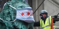 CHICAGO, ILLINOIS - APRIL 30: Keith Walsh puts a mask with a depiction of the Chicago flag over the face of one of the lion sculptures that stand in front of the Art Institute on April 30, 2020 in Chicago, Illinois. On May 1, the state of Illinois will begin requiring everyone to wear a face mask in public when social distancing is not possible to prevent the spread of the coronavirus COVID-19.  (Photo by Scott Olson/Getty Images)
