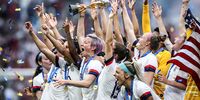 Megan Rapinoe of the USA lifts the FIFA Women's World Cup Trophy following her team's victory in the 2019 FIFA Women's World Cup France Final match between The United States of America and The Netherlands at Stade de Lyon on July 07, 2019 in Lyon, France. (Photo by Alex Grimm/Getty Images)