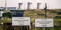 Signs for Optimum Pullenshope opencast and underground mining sites stand at the entrance to the Optimum Colliery, owned by Glencore Plc, which supplies coal to the Hendrina power station, top, operated by Eskom Holdings SOC Ltd., in Middelburg, South Africa, on Wednesday, April 13, 2016. (Photo: Waldo Swiegers/Bloomberg via Getty Images)