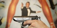 LONDON - NOVEMBER 02:  A Walther PPK handgun is held up infront of a poster of the film 'For Your Eyes Only' during promotion of a sale of weapons from James Bond films on November 2, 2006 in London. Actor Daniel Craig will play Bond in 'Casino Royale' the 21st film made from author Ian Fleming's books. Christie's Film and Entertainment sale takes place on December 5, 2006.  (Photo by Peter Macdiarmid/Getty Images)