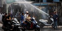 People on their scooters pass under a water sprinkler on a hot summer day in Ahmedabad, India, May 9, 2024. REUTERS/Amit Dave     TPX IMAGES OF THE DAY