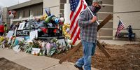 BOULDER, CO - MARCH 26: A man who drove in from Indiana carries a cross and an American flag as he pays his respects to slain Boulder Police officer Eric Talley at a makeshift memorial outside the Boulder Police Station on March 26, 2021 in Boulder, Colorado. Ten people, including Talley, were killed in a shooting at a nearby King Soopers grocery store on Monday. (Photo by Michael Ciaglo/Getty Images)