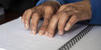 Nadiem Marthinus, who is blind, learns how to read braille at the Cape Town Society for the Blind on July 12, 2022 in Cape Town, South Africa.  Braille is a system of raised dots that can be read with the fingers by people who are blind or who have low vision. (Photo by Gallo Images/Daily Maverick/Leila Dougan)
