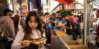 On a famous nightmarket, people join crowds to eat Takoyaki, small pancake balls filled with octopus. (Photo: Nathalie Bertrams)