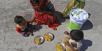 A migrant worker that was unable to catch a bus feeds her children on the side of National Highway 24 during the lockdown. (Photo: Anindito Mukherjee / Bloomberg via Getty Images)