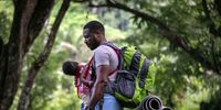 ACANDI, COLOMBIA - OCTOBER 07: A Haitian father holds his infant while pausing on a trek through the Darien Gap in route to the United States on October 07, 2021 near Acandi, Colombia. The passage through dense rainforest is considered the most dangerous stretch for migrants traveling from South America to the U.S. During the trip, torrential downpours lead to sudden river floodings, often resulting migrant drownings along the way. Reports of robberies and rapes are common, especially after migrants pass the remote mountain border crossing from Colombia into Panama. More than 70,000 migrants have traveled through the Darien Gap this year, according to Panamanian authorities. Most of the migrants in recent months have been Haitians, many of whom had been living in Chile and Brazil since the 2010 Haitian earthquake. The Darien Gap is the 66-mile stretch of rainforest between North and South America where the Panamerican Highway was never completed due to severe terrain, enormous cost and myriad environmental concerns. (Photo by John Moore/Getty Images)