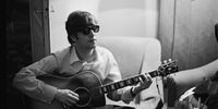 John Lennon (1940 - 1980) of the Beatles plays the guitar in a hotel room in Paris, 16th January 1964. (Photo by Harry Benson/Express/Hulton Archive/Getty Images)