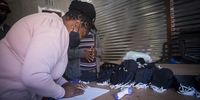 Ponani Shikweni records the temperatures of her staff in a register. The mother of three is cautious when it comes to the safety of her kids. (Photo: Shiraaz Mohamed)