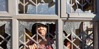 Hlengiwe Ntuli peers from the shattered windows of her home on Magwaveni, Tongaat.( Photo: Tony Carnie)