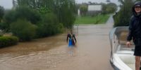 A brave volunteer wades across a flooded Queen Victoria Street to get to people who have been<br>cut off from the village. (Photo: Rodney Ackerman)