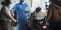 A healthcare worker talks to a patient in the triage area as he waits to be screened. (Photo: Shiraaz Mohamed)