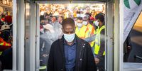 A commuter wearing a protective face mask walks through a sanitation tunnel at the Rea-Vaya Thokoza Park bus station in the Soweto district of Johannesburg, South Africa, on Thursday, May 14, 2020. South Africa's government announced plans to further ease a nationwide lockdown as the fallout from shuttering much of the economy threatens to outweigh the damage wrought by the coronavirus. Photographer: Waldo Swiegers/Bloomberg via Getty Images