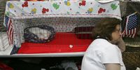 A woman rests near a cat in a cage during the 18th Annual Cat Fanciers' Association International Cat Show November 18, 2005 in San Mateo, California. The three-day CFA International Cat Show is the largest pedigreed cat show, featuring more than 800 felines and representing 41 breeds. The show runs through Sunday when one cat will be awarded the coveted "best in Show" title.  (Photo by Justin Sullivan/Getty Images)