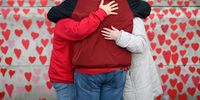LONDON, ENGLAND - MARCH 29: Members of the public view the photos of some of those who died during the Covid-19 pandemic, on the first anniversary of the creation of the Covid Memorial Wall, on March 29, 2022 in London, England. Bereaved family members and teams of volunteers painted around 145,000 hearts along a half-mile stretch of wall opposite the Houses of Parliament in memory of their relatives who died from Covid-19 during the Coronavirus Pandemic.   (Photo by Leon Neal/Getty Images)