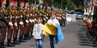 LVIV, UKRAINE - AUGUST 24: Two boys walk with a flag as dignitaries and members of the public attend a ceremony in the Na Valakh park on Independence Day of Ukraine on August 24, 2022 in Lviv, Ukraine. This year, Ukraine's Independence Day, commemorating its break with the Soviet Union in 1991, coincides with the six-month mark since Russia launched its large-scale invasion of the country. The fighting has largely focused on the eastern Donbas region and the south, but most anywhere in Ukraine remains vulnerable to Russian air strikes. (Photo by Jeff J Mitchell/Getty Images)
