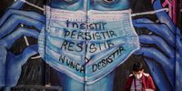 BOGOTA, COLOMBIA - JUNE 21: A woman walks in front of a mural that reads "insist, persist, resist and never give up" amid the coronavirus (COVID-19) pandemic on June 21, 2021 in Bogota, Colombia. According to the last official report by the Ministry of Health and Social Protection, Colombia recently registered 99,934 victims of COVID-19. With over 500 deaths in the last 24 hours, the country expects to reach 100,000 victims today. (Photo by Diego Cuevas/Getty Images)