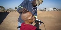 A man has his hair shaved as he sits outside. In an effort to take better care of the elderly, caregivers have increased their social activities. (Photo: Shiraaz Mohamed)