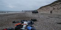 epa09602228 Policemen walk next to migrants' personal belongings left behind on the beach near Wimereux, France, 25 November 2021. At least 27 migrants have died and two others have been taken to hospital after a boat in which they were trying to cross the La Manche canal (English Channel) to Great Britain sank on 24 November.  EPA-EFE/MOHAMMED BADRA